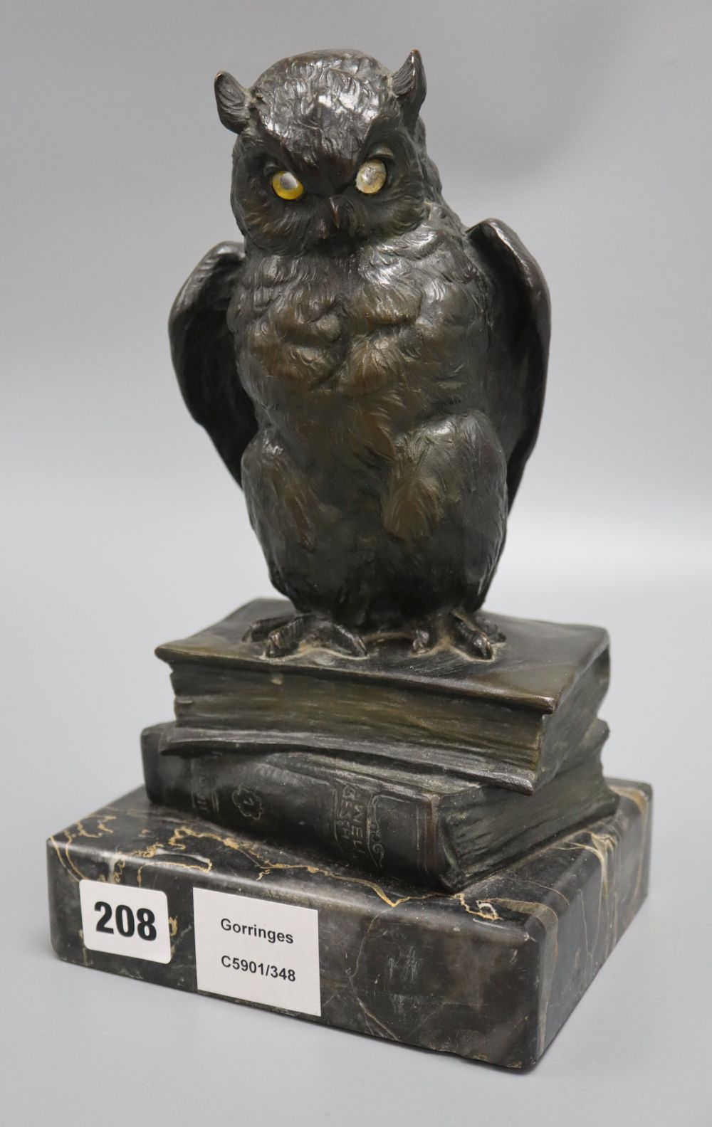 An early 20th century German bronze of an owl, with glass eyes, perched on a stack of two books, on marble base, height 26cm